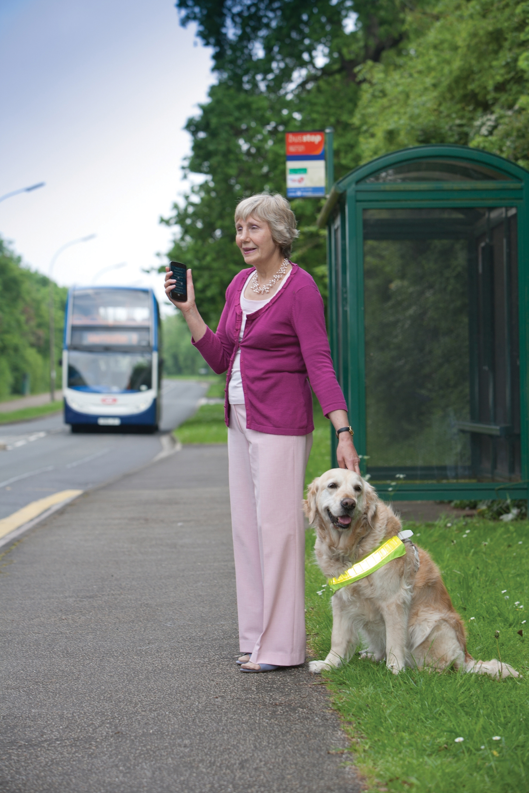 Blind lady with dog standing my bus stop